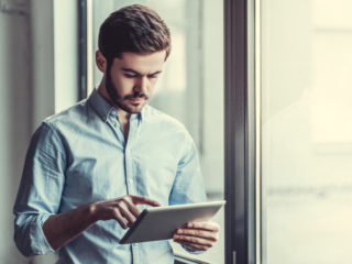 Man using a tablet to access AccuLynx material supplier integrations for ordering.