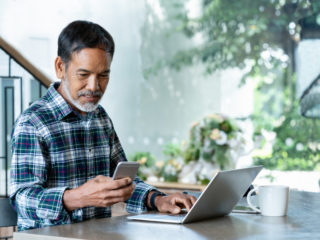 man using roof management software on a laptop and phone.