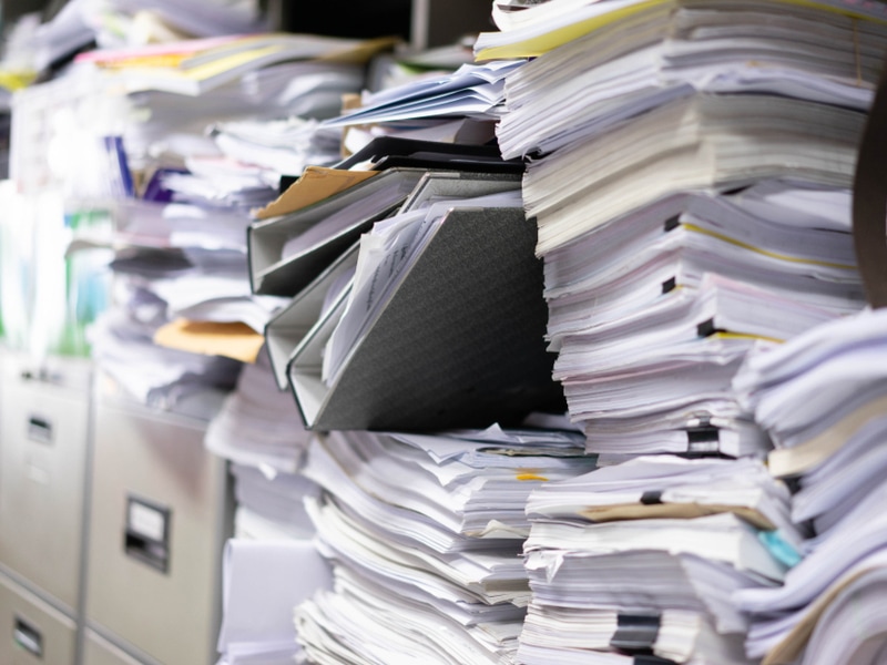 file cabinets with paperwork spilling over the top due to lack of digital roofing documents