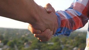 People shaking hands to signify a roofing sales team closing a deal.