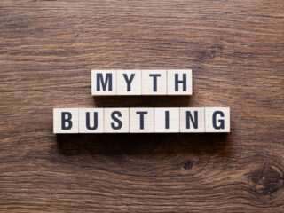 Blocks that say myth busting on wood background.