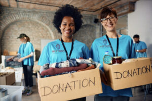 Two women that work for a roofing company volunteering at a charity drive they are sponsoring. 