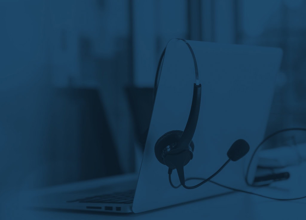A laptop with a headset hanging off of the monitor