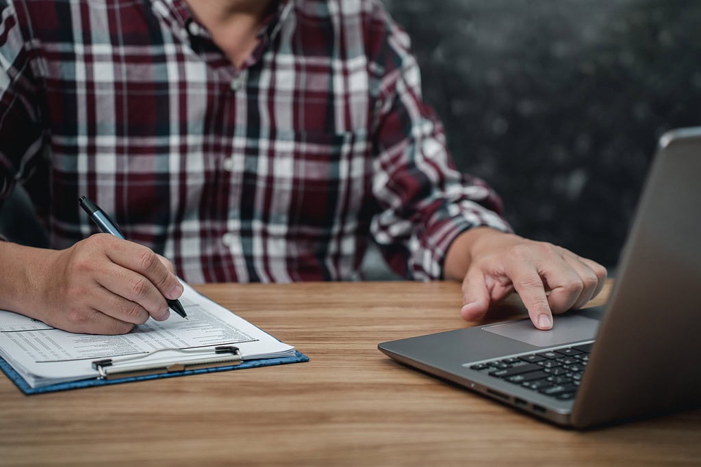 Man wears a comfortable plaid shirt working in the home office checking the document from laptop