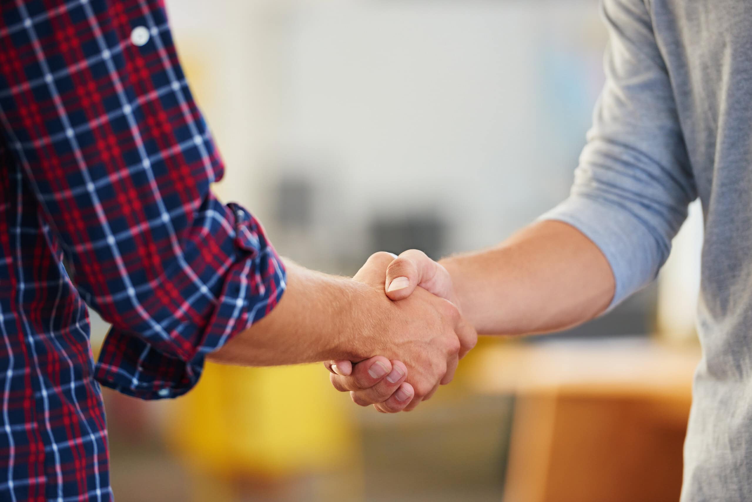 Closeup shot of two men shaking hands in a casual office.