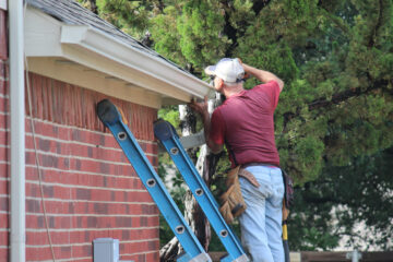 Man on a ladder inspecting a roof